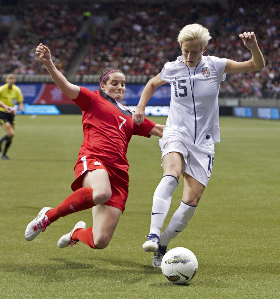 VANCOUVER, CANADA - JANUARY 29: Rhian Wilkinson #7 of Canada makes a sliding tackle to knock the ball away from Mega Rapinoe #15 of the United States during second half of championship action of the 2012 CONCACAF Women's Olympic Qualifying Tournament at BC Place on January 29, 2012 in Vancouver, British Columbia, Canada. (Photo by Rich Lam/Getty Images)