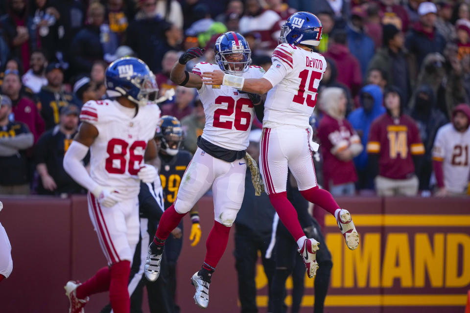 New York Giants running back Saquon Barkley (26) celebrating his touchdown against the Washington Commanders with quarterback Tommy DeVito (15) during the first half of an NFL football game, Sunday, Nov. 19, 2023, in Landover, Md. (AP Photo/Andrew Harnik)