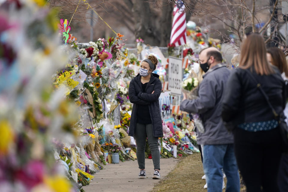 Mourners walk along the temporary fence put up around the parking lot of a King Soopers grocery store where a mass shooting took place earlier in the week, in Boulder, Colo., Thursday, March 25, 2021. (AP Photo/David Zalubowski)