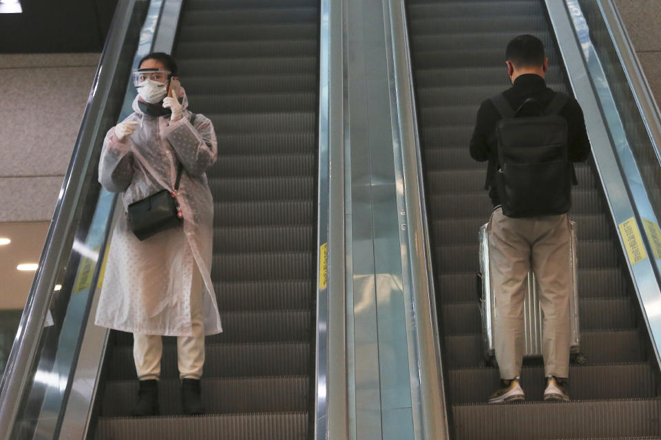 A woman wearing a mask, goggles and rain coat comes down the escalator at Incheon International Airport in Incheon, South Korea, Tuesday, Feb. 25, 2020. China and South Korea on Tuesday reported more cases of a new viral illness that has been concentrated in North Asia but is causing global worry as clusters grow in the Middle East and Europe.(AP Photo/Ahn Young-joon)