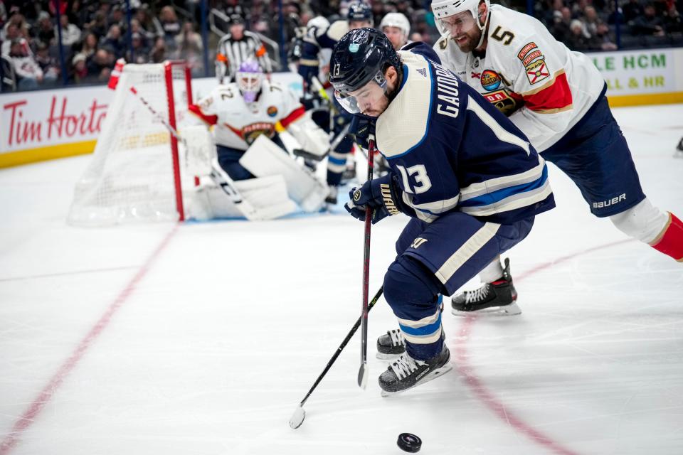 Nov 20, 2022; Columbus, Ohio, United States;  Columbus Blue Jackets forward Johnny Gaudreau (13) fights to keep the puck away from Florida Panthers defenseman Aaron Ekblad (5) during the third period of the NHL hockey game at Nationwide Arena. Mandatory Credit: Joseph Scheller-The Columbus Dispatch