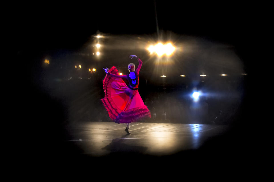 In this Nov. 3, 2019, photograph a ballerina of the Arabesque Children's Ballet Ensemble, seen through a hole in the stage curtains performs during a show featuring children with the Down syndrome, in Bucharest, Romania. Children with Down syndrome staged a fashion show and performed along a ballet ensemble, two milestone events for the inclusion of people with disabilities in Romania's social life, 30 years after the fall of communism following a violent uprising at the end of 1989.(AP Photo/Andreea Alexandru)