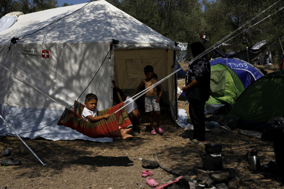 A child plays on a makeshift swing near the burned Moria camp on island of Lesbos, Greece, Sunday Sept. 13, 2020. Greek authorities have been scrambling to find a way to house more than 12,000 people left in need of emergency shelter on the island after the fires deliberately set on Tuesday and Wednesday night gutted the Moria refugee camp. (AP Photo/Petros Giannakouris)