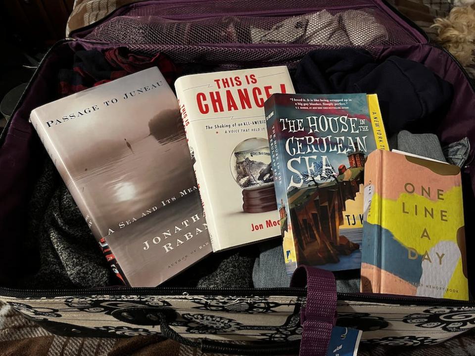 Four different books laid out in a suitcase
