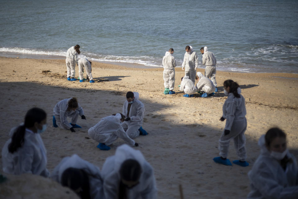 Israeli soldiers wearing protective suits clean tar from a beach after an oil spill in the Mediterranean Sea in Sharon Beach Nature Reserve, near Gaash, Israel, Monday, Feb. 22, 2021. (AP Photo/Ariel Schalit)