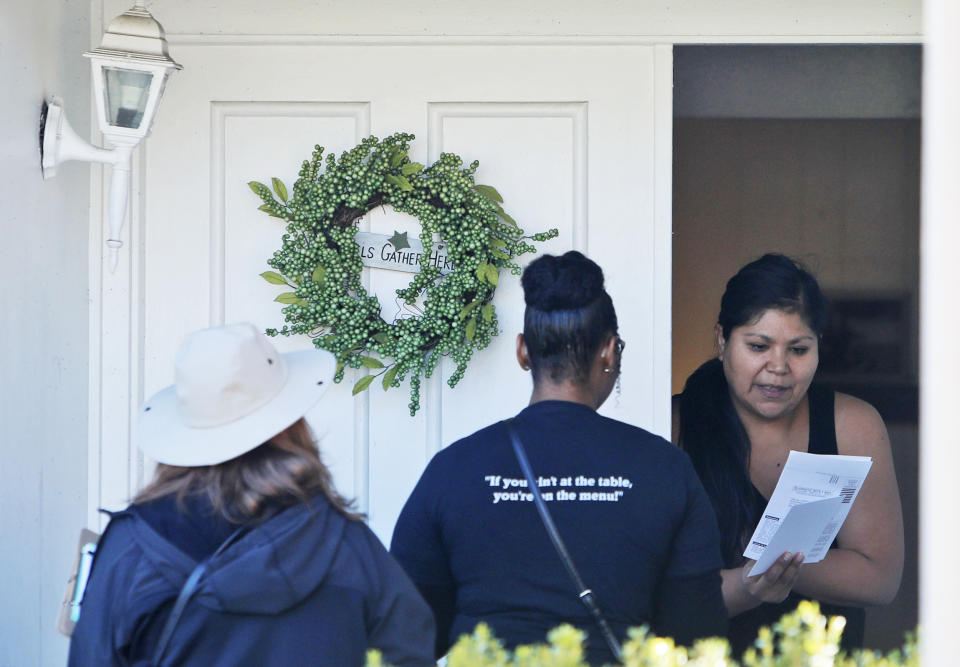 A resident takes voter registration paperwork from Democratic Party Precinct Chairs Angela Orr Heath, center, and Myla Senn, left, during for a voter registration drive in Garland, Texas, on Jan. 18, 2020. (LM Otero / AP)