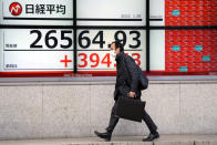 A man wearing a protective mask walks in front of an electronic stock board showing Japan's Nikkei 225 index at a securities firm Friday, Jan. 28, 2022, in Tokyo. Asian stock markets were mixed Friday as traders looked ahead to data on U.S. employment costs that might influence Federal Reserve decisions on planned interest rate hikes. (AP Photo/Eugene Hoshiko)