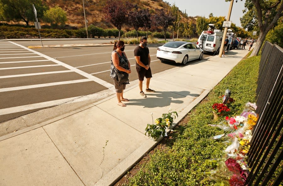 Lorraine Maralian and her son Anthony Maralian of Westlake Village place flowers and pray at a growing memorial for two brothers who were fatally injured while crossing Triunfo Canyon Road at Saddle Mountain Drive in their Westlake Village neighborhood on Wednesday, Sept. 30, 2020 in Westlake Village, CA. (Al Seib / Los Angeles Times)
