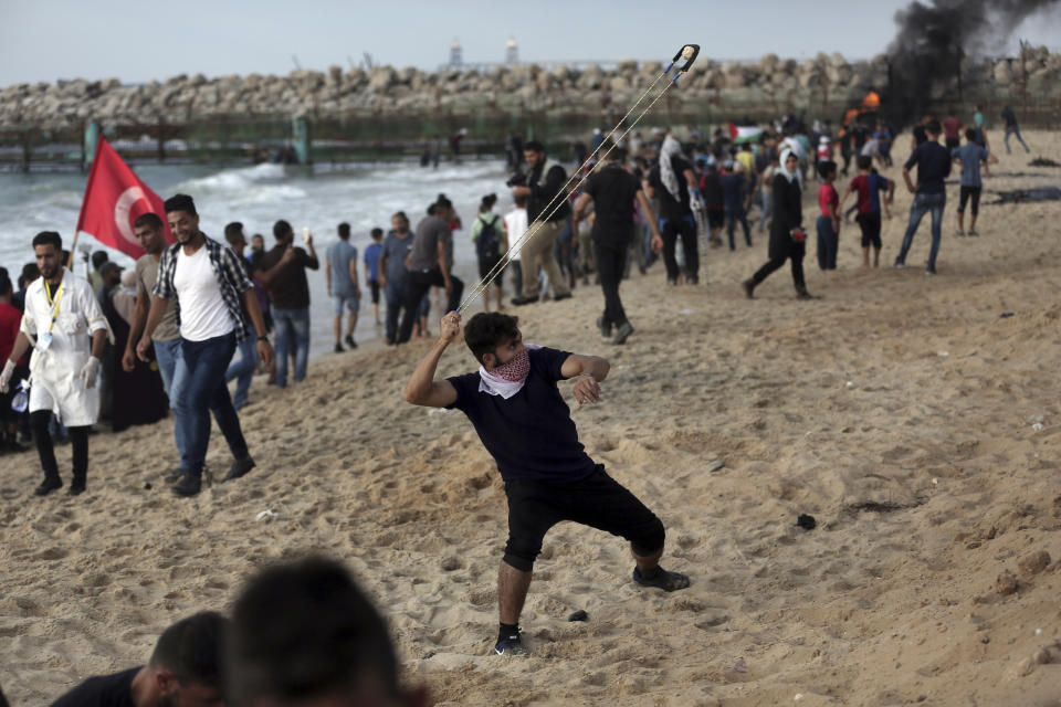 A Palestinian protester hurls stones during a protest on the beach at the border with Israel near Beit Lahiya, northern Gaza Strip, Monday, Oct. 8, 2018.(AP Photo/Khalil Hamra)