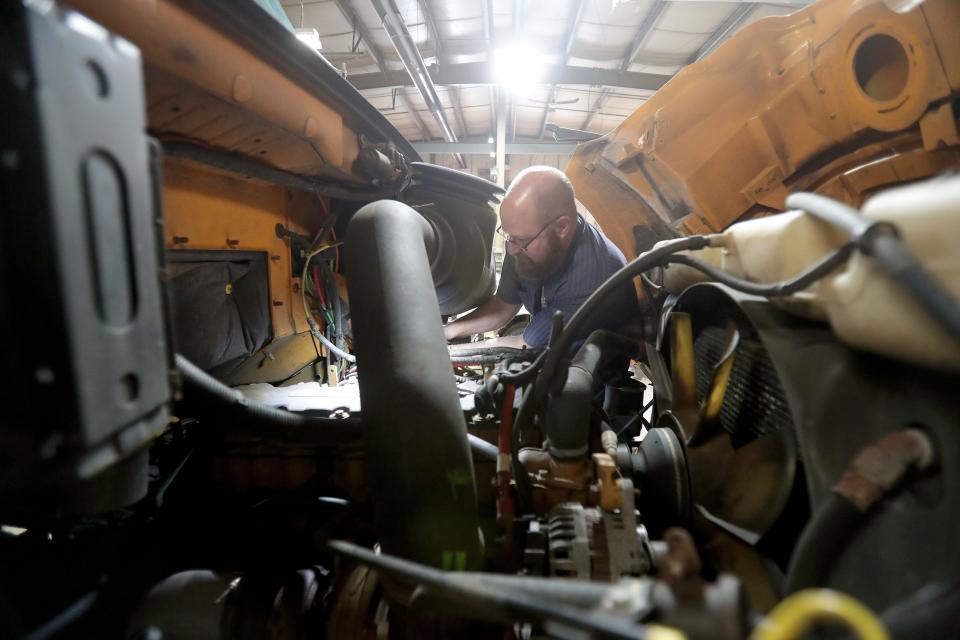 Tim Corbi, a Perry Road Department mechanic, replaces a coolant temperature sensor on a township dump truck Tuesday morning.