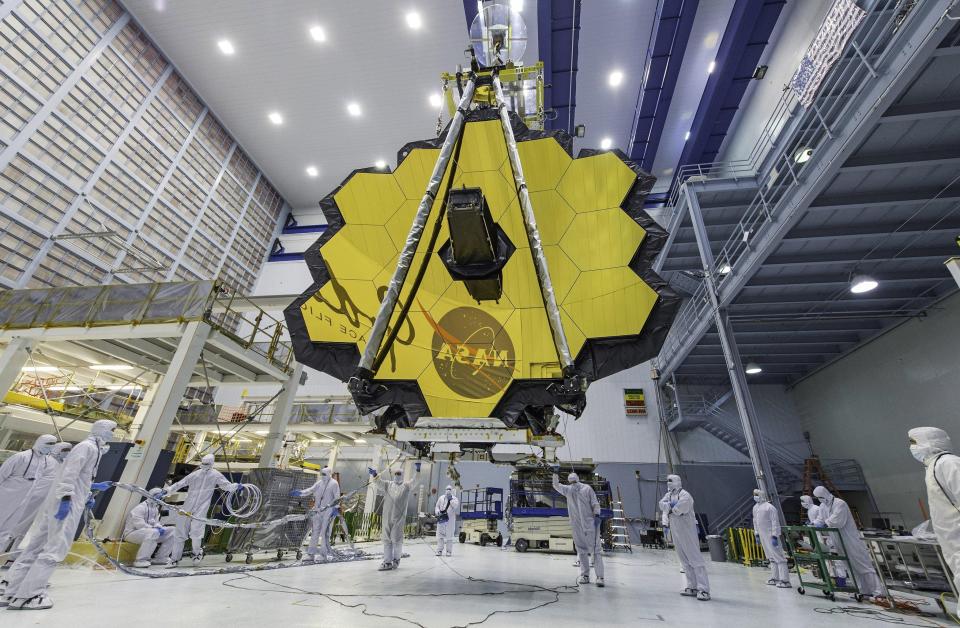 Technicians lift the mirror of the James Webb Space Telescope using a crane at the Goddard Space Flight Center in Greenbelt, Maryland. The telescope's 18-segmented gold mirror is specially designed to capture infrared light from the first galaxies that formed in the early universe.