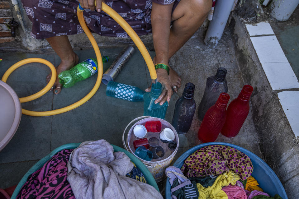 A woman fills bottles with water on her front porch to keep at home in Dharavi, one of Asia's largest slums, in Mumbai, India, Wednesday, May 3, 2023. Water arrives each day from 6 to 9 a.m. in the neighborhood, an area teeming with working families. It causes a rush of activity in the extreme heat of spring and summer. (AP Photo/Dar Yasin)