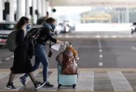 Women wear protective face masks at international arrivals area at Guarulhos International Airport, amid coronavirus fears, in Guarulhos