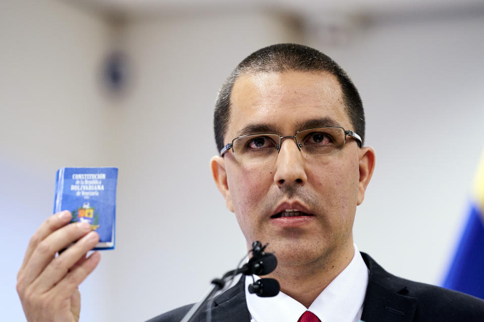 Venezuela's Foreign Minster Jorge Arreaza holds a copy of the constitution as he speaks during a press conference after visiting the International Criminal Court in The Hague, Netherlands, Thursday, Feb. 13, 2020. (AP Photo/Phil Nijhuis)