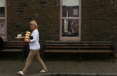 A woman walks past an empty building which has been covered with artwork to make it look more appealing, in the village of Bushmills on the Causeway Coast August 20, 2013. REUTERS/Cathal McNaughton