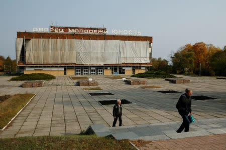 People walk near the "Yunost" (Youth) concert hall which was damaged by shelling in central Donetsk, Ukraine, October 18, 2017. REUTERS/Alexander Ermochenko