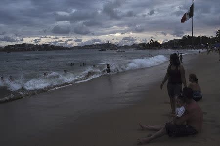 People spend time at the beach in Acapulco, as Hurricane Odile churns far off shore September 14, 2014. (REUTERS/Claudio Vargas)