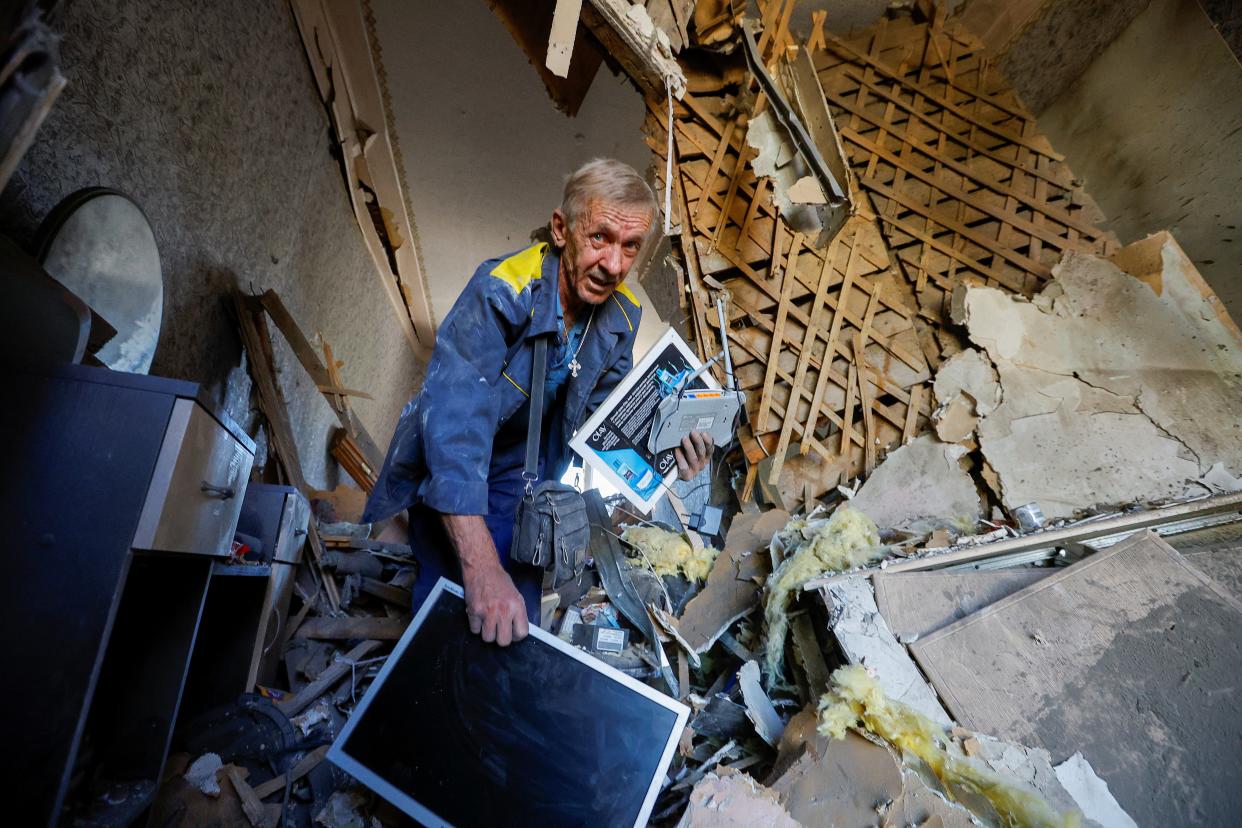 A man carries belongings inside a house heavily damaged by recent shelling (REUTERS)