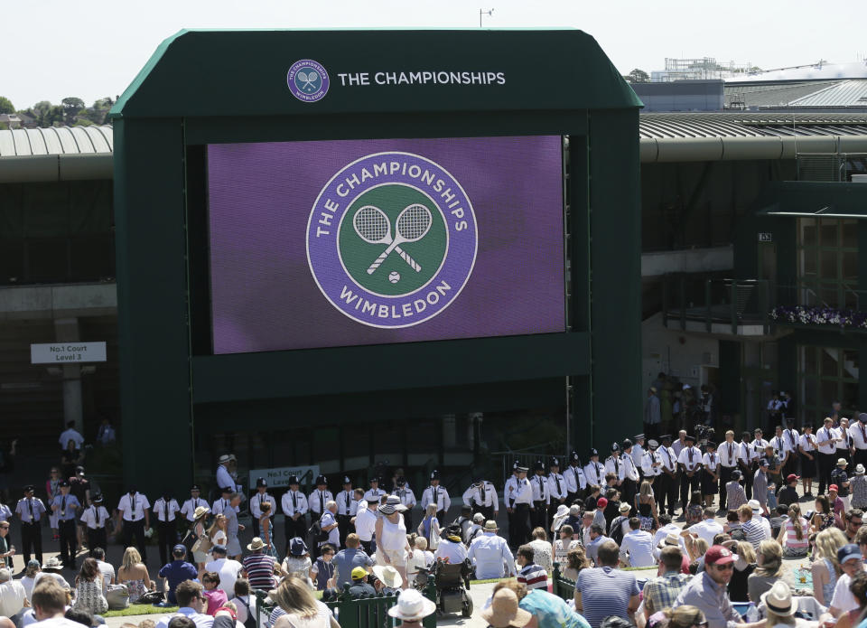 FILE - British police officers line up under the big screen on Murray Mount, ahead of the minute silence for the victims of the shooting in Tunisia last week, at the All England Lawn Tennis Championships in Wimbledon, London, Friday July 3, 2015. Tennis could be on the verge of massive structural change if separate proposals formulated by the four Grand Slam tournaments and the WTA and ATP professional tours can succeed. (AP Photo/Tim Ireland, File)