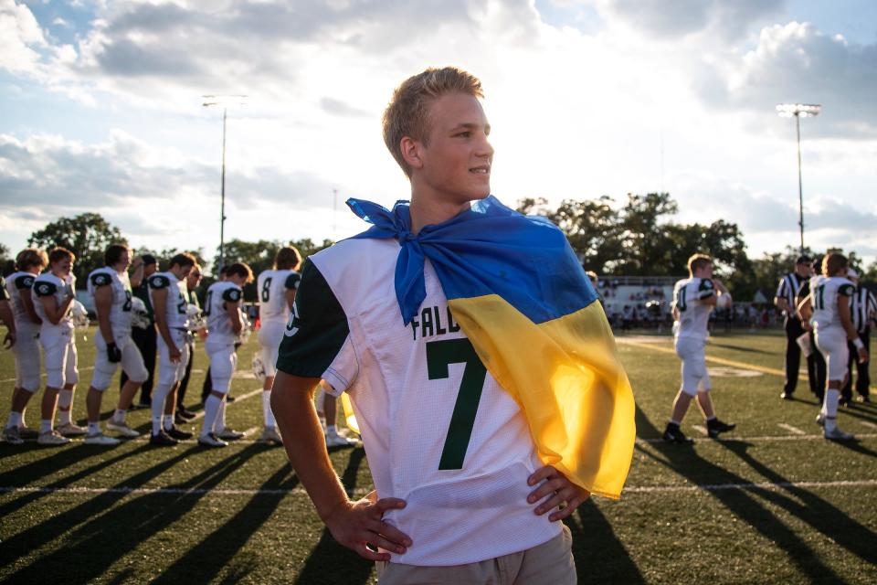 Grand Rapids West Catholic football player Hlib Kuzmenko of Ukraine wears a Ukrainian flag over his shoulder standing on the sideline ahead of a game against Ferndale High School in Ferndale on Thursday, Sept. 1, 2022.