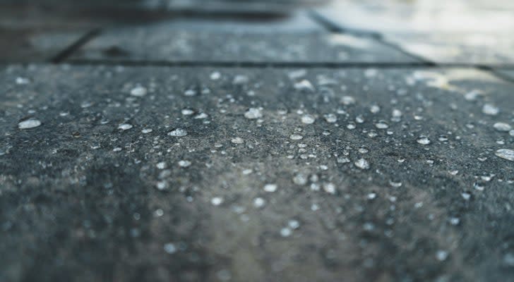 A photograph of rain droplets on a concrete surface.