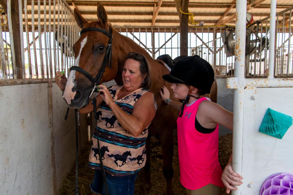 Connie Almond, left, helps granddaughter Avery Keown adjust the bridle on Deuce before participating in the 4-H horse and pony english show at the 102nd Vanderburgh County Fair in Evansville, Ind., Tuesday, July 25, 2023.