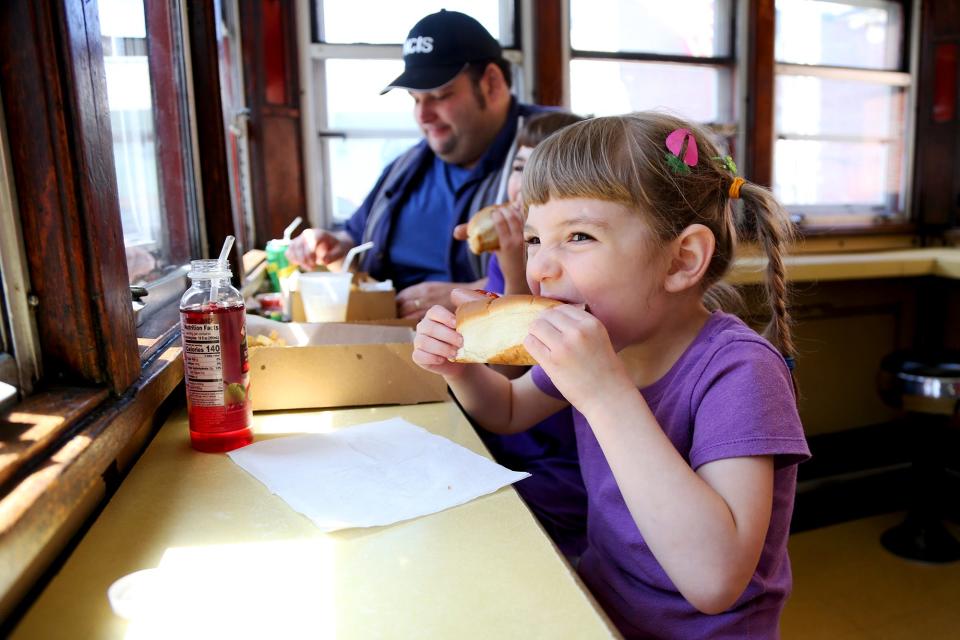 A Gilley’s hot dog is one of 101 objects that help tell Portsmouth’s story. Here, Portsmouth resident Elizabeth Ouellette, 4, bites into a hot dog at Gilley’s Diner in May, 2022.