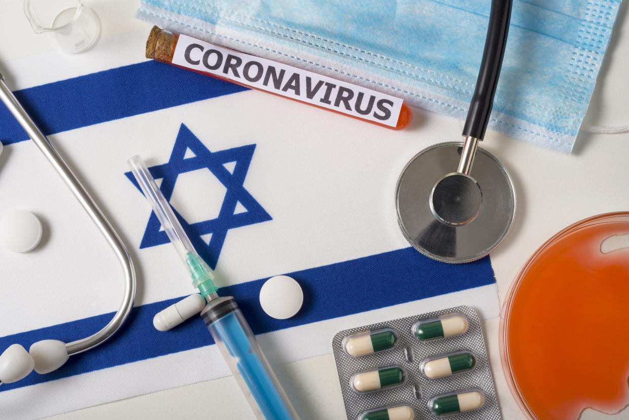 Coronavirus, nCoV concept. Top view of a protective breathing mask, stethoscope, syringe, pills on the flag of Israel. A new outbreak of the COVID-19