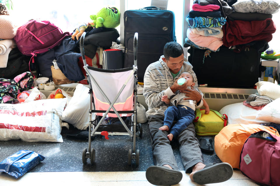 CHICAGO, ILLINOIS - MAY 09: A migrant father from Venezuela feeds his 15-month-old son in the lobby of a police station where they have been staying with other migrant families since their arrival to the city on May 09, 2023 in Chicago, Illinois. Chicago Mayor Lori Lightfoot issued a state of emergency on Tuesday amid a surge in migrant arrivals which began in August 2022 when the first group of immigrants were bused from Texas to Chicago by Texas Gov. Greg Abbott. According to Lightfoot's office, more than 8,000 migrants have arrived in Chicago since last year, with the city currently reaching 