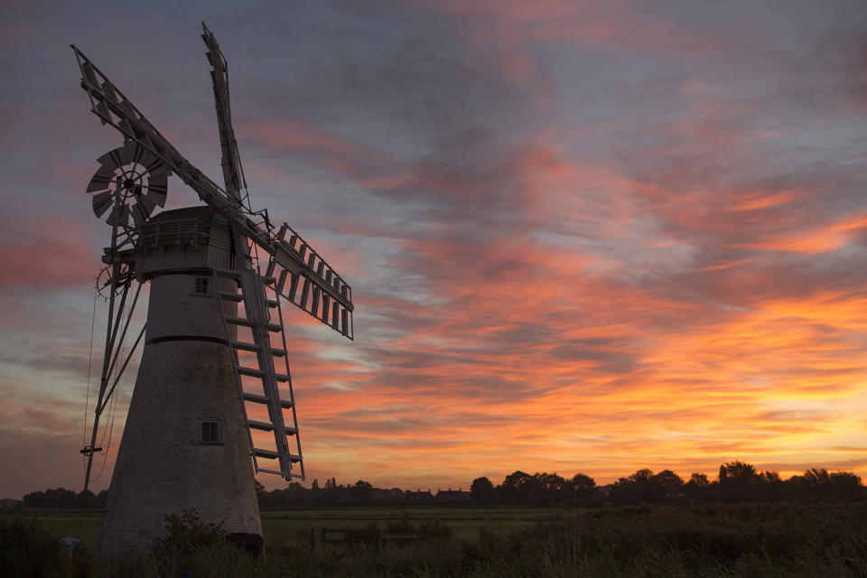 <p>The sun rises behind Thurne Mill on Aug. 24, 2016 on The Broads, England. The Norfolk Broads are a network of mostly navigable rivers and broads or lakes, encompassing around 303 square kilometres and crossing the two counties of Norfolk and Suffolk. (Photo: Dan Kitwood/Getty Images) </p>