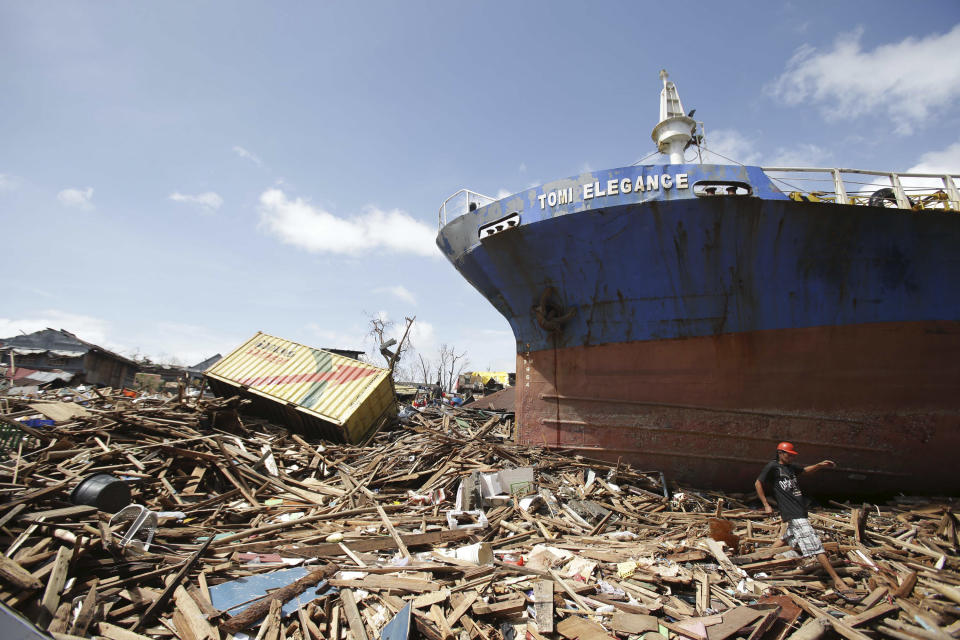 En esta fotografía del 10 de noviembre de 2013, un sobreviviente camina al lado de un barco que fue llevado a tierra por las fuertes olas causadas por el tifón Haiyan en la ciudad de Tacloban, Filipinas. Las tormentas poderosas como Haiyan quizá no sean causadas por el calentamiento global, pero sus letales marejadas son intensificadas por el aumento del nivel del mar derivado del cambio climático, dijo Maarten van Aalst, un alto funcionario de la Federación Internacional de Sociedad de la Cruz Roja y la Media Luna Roja. (Foto AP/Aaron Favila/Archivo)