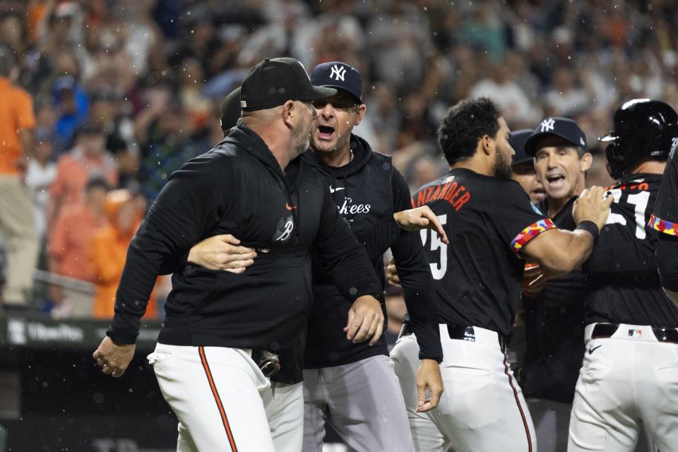 CORRECTS NAME TO ORIOLES MANAGER BRANDON HYDE - New York Yankees manager Aaron Boone, center, and Baltimore Orioles manager Brandon Hyde, left, argue after players cleared the benches during the ninth inning of a baseball game, Friday, July 12, 2024, in Baltimore. (AP Photo/Stephanie Scarbrough)