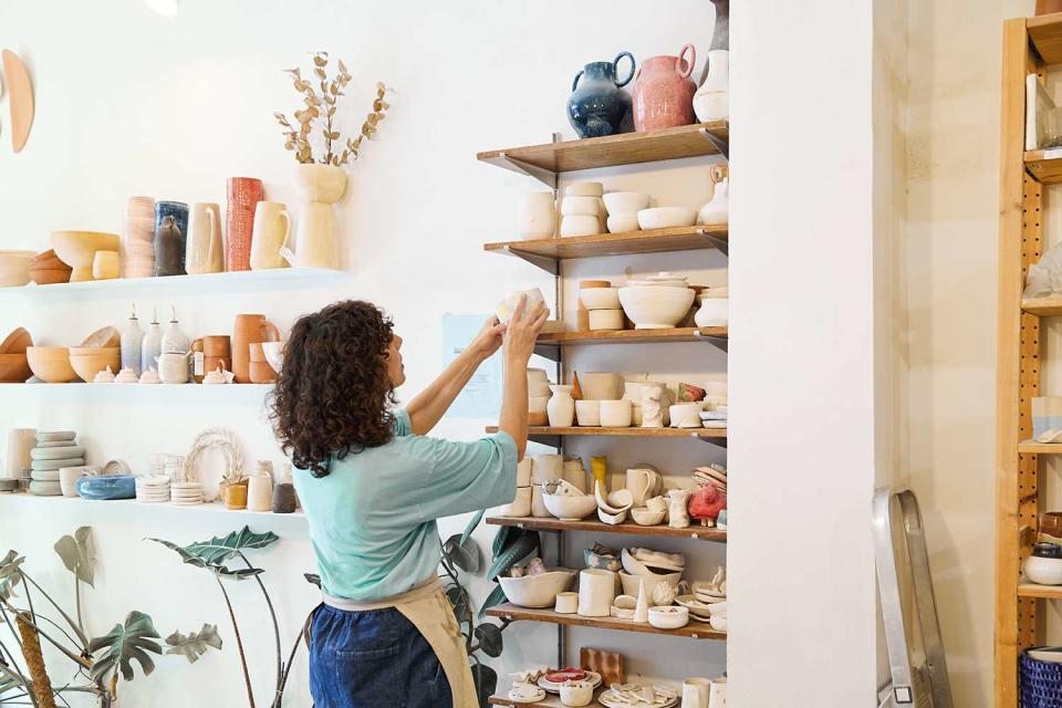 <p>Javi Sanz/Getty</p> A stock image of a woman looking at ceramic products