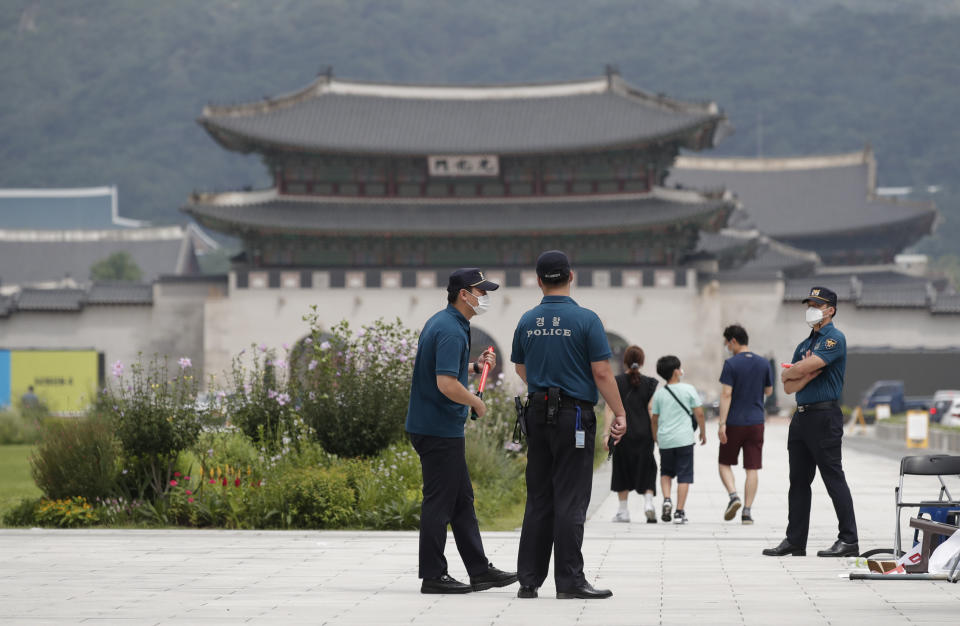 Police officers and visitors wearing face masks to help protect against the spread of the coronavirus, walk in downtown Seoul, South Korea, Sunday, Aug. 16, 2020. South Korea has reported 279 new coronavirus cases in the highest daily jump since early March, as fears grow about a massive outbreak in the greater capital region.(AP Photo/Lee Jin-man)