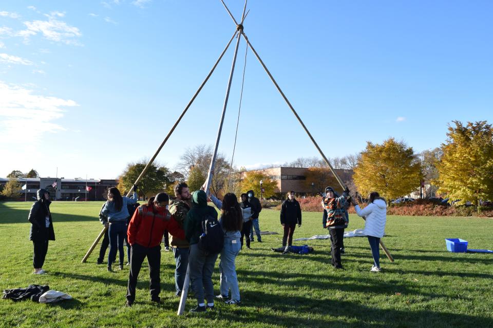 Students, faculty, staff and community members set up the three tallest poles of a tipi on campus at the University of South Dakota on Nov. 1, 2021 in honor of Native American Heritage Month.