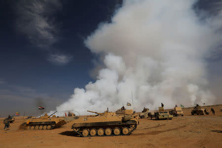 Iraqi army gather after the liberation of a village from Islamic State militants, south of Mosul, as toxic smoke is seen over the area after Islamic State militants set fire to a sulphur factory. REUTERS/Thaier Al-Sudan