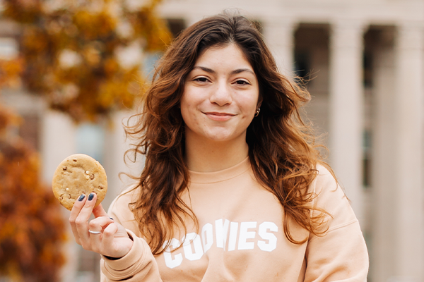 Purdue University student Abby Haluska holds the The Cinnamon Bun Filled Deluxe cookie she created after winning last year’s Insomnia Cookies ultimate cookie lover Instagram and TikTok contest.