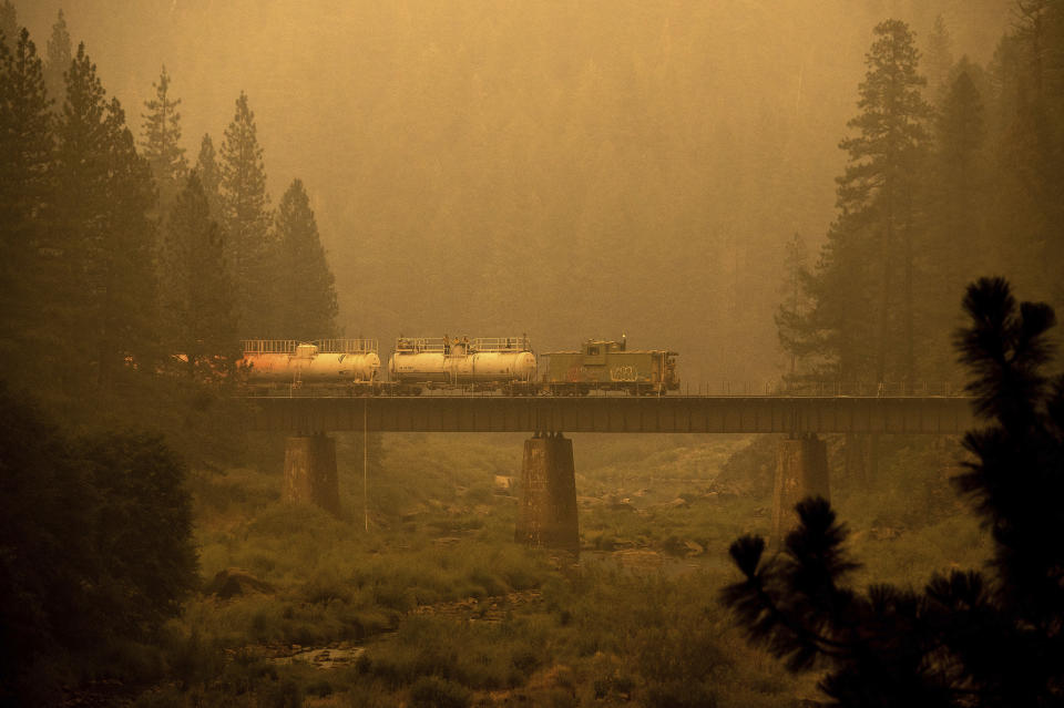 A fire train crosses a bridge as the Dixie Fire burns in Plumas County, Calif., on Saturday, July 24, 2021. The train is capable of spraying retardant to coat tracks and surrounding land. (AP Photo/Noah Berger)