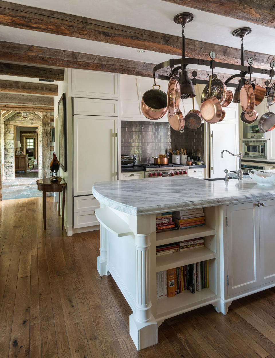 white rustic kitchen with beamed ceiling and ceiling storage above white island