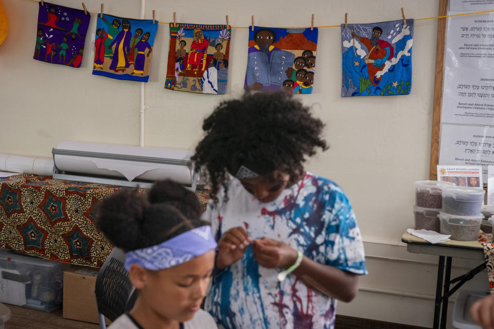 Campers work on art projects in front of tapestries of illustrated Bible scenes made in Ethiopia, during Camp Be'chol Lashon, a sleepaway camp for Jewish children of color, Friday, July 28, 2023, in Petaluma, Calif., at Walker Creek Ranch. Several of the campers are Ethiopian adoptees meeting for the first time at camp. (AP Photo/Jacquelyn Martin)