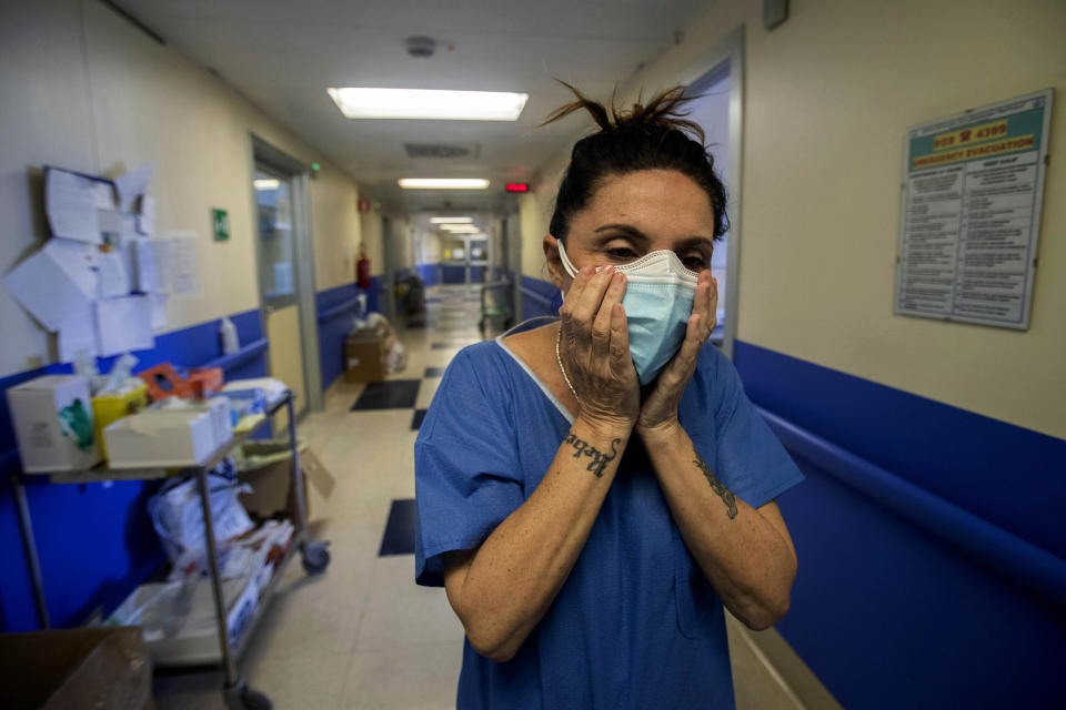 Nurse Cristina Settembrese fixes two masks to her face during her work shift in the COVID-19 ward at the San Paolo hospital in Milan, Italy, April 10, 2020. Settembrese spends her days caring for COVID-19 patients in a hospital ward, and when she goes home, her personal isolation begins by her own choice. (AP Photo/Luca Bruno)