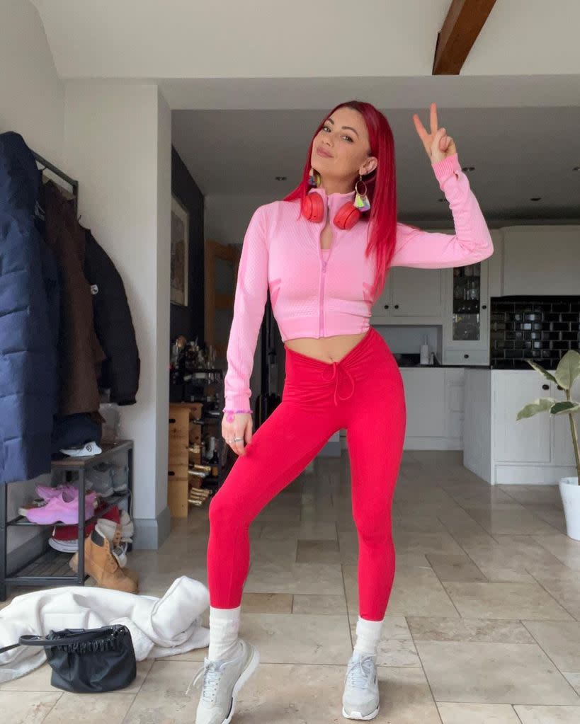 Dianne Buswell posing in a pink and red gym set