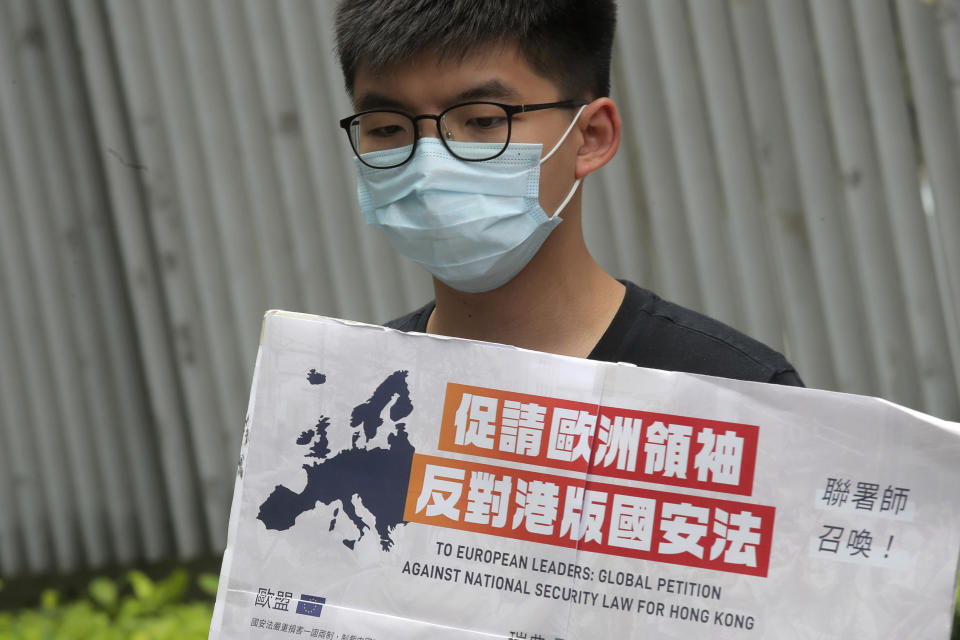 Pro-democracy activists Joshua Wong, holding a placard, speaks to media to urge the European leaders against national security law for Hong Kong outside the Legislative Council, in Hong Kong, Wednesday, June 3, 2020. Hong Kong legislative council resumes debate on a bill criminalizing abuse of the Chinese national anthem in the semi-autonomous city. (AP Photo/Kin Cheung)