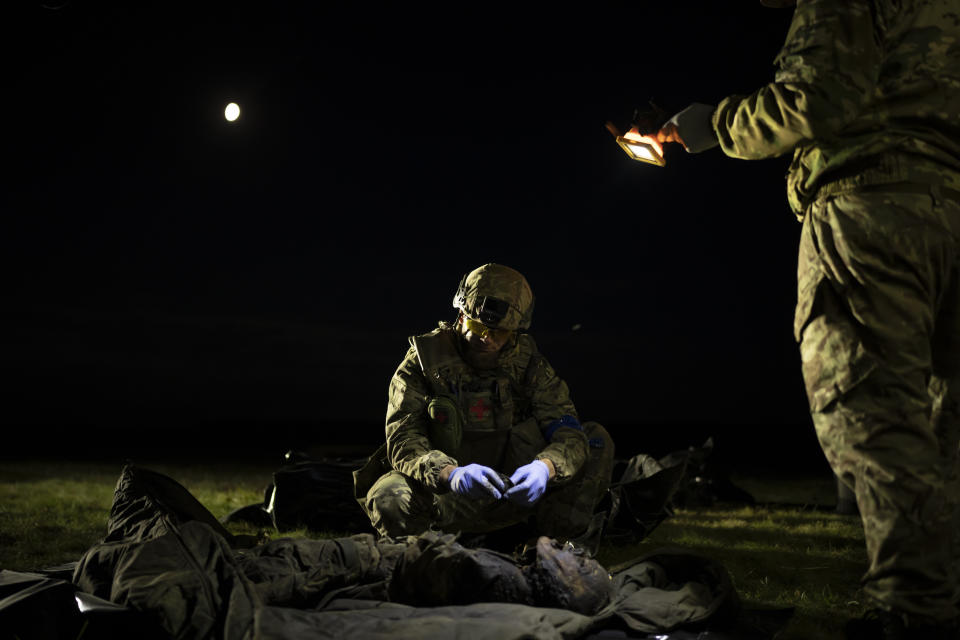 Oleksii Yukov examines the body of a Russian soldier he collected on the frontline in the Sloviansk region, Ukraine, Tuesday, Oct. 24, 2023. Yukov understands that for people far away, war is geopolitics, death can be counted in numbers, and money matters more than men. But he knows better. “War has one face,” he said. “Death and stupidity and horror.” (AP Photo/Bram Janssen)