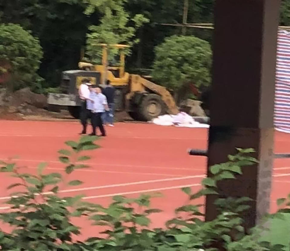 Police officers digging up the school running track where a Chinese teacher's body was found after he disappeared 16 years ago. 
