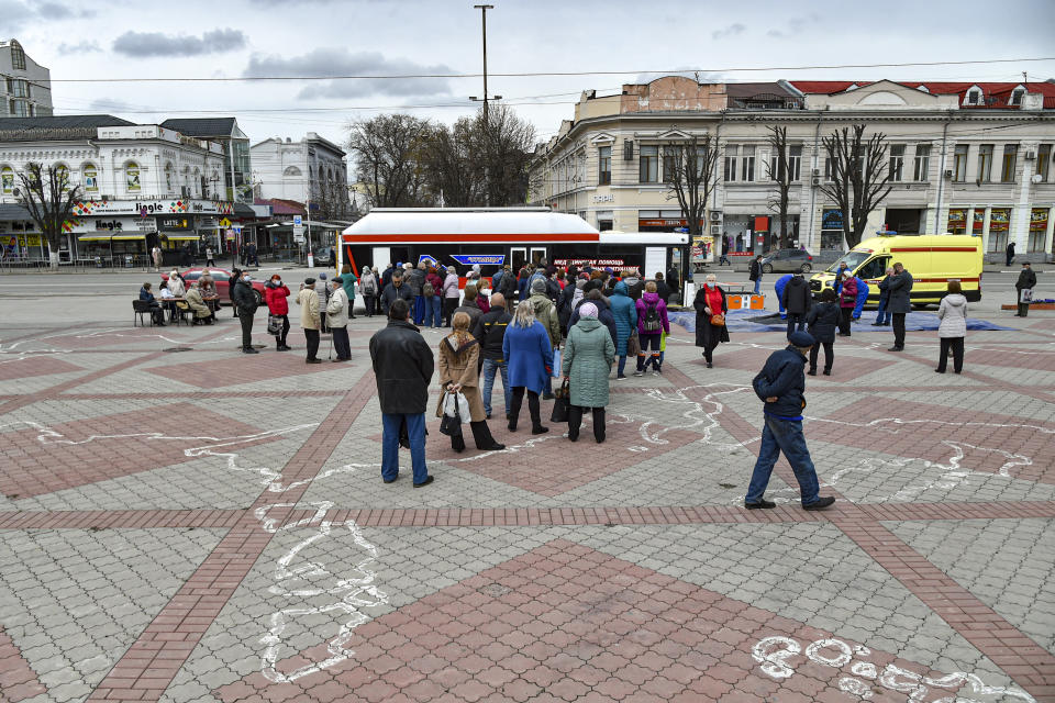 People wearing face masks to protect against coronavirus queue to get a shot of Russia's Sputnik V coronavirus vaccine in a mobile vaccination center in Simferopol, Crimea, Tuesday, April 13, 2021. Russia has boasted about being the first country in the world to authorize a coronavirus vaccine and rushed to roll it out earlier than other countries, even as large-scale testing necessary to ensure its safety and effectiveness was still ongoing. (AP Photo/Alexander Polegenko)