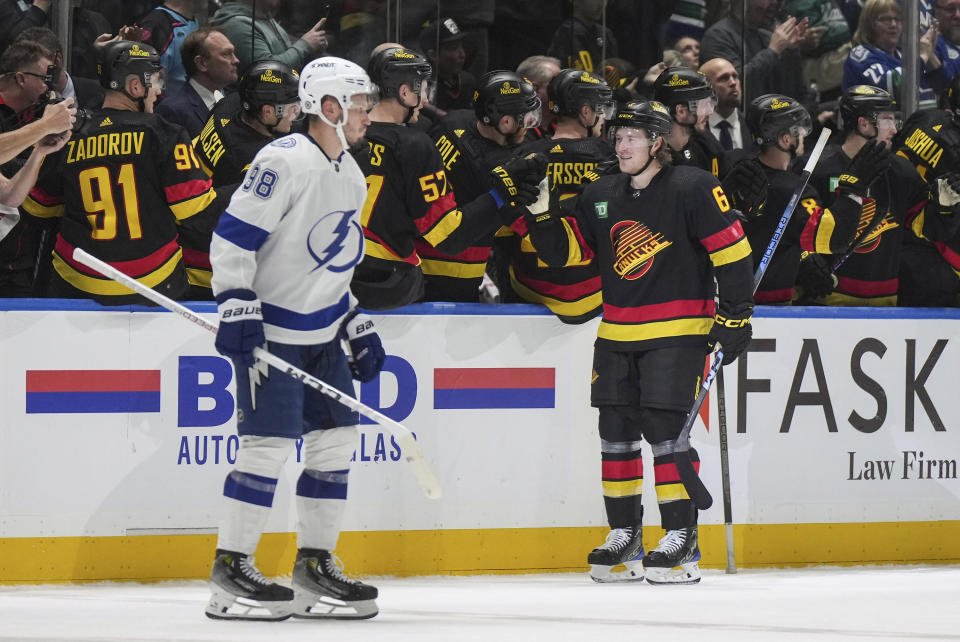 Vancouver Canucks' Brock Boeser (6) celebrates his goal as Tampa Bay Lightning's Mikhail Sergachev skates past during the second period of an NHL hockey game in Vancouver, B.C., on Tuesday, Dec. 12, 2023. (Darryl Dyck/The Canadian Press via AP)
