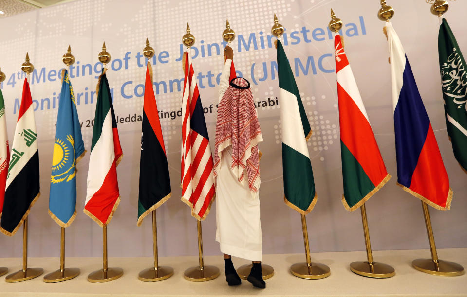 A Saudi worker adjusts flags of participating countries before a meeting of energy ministers from OPEC and its allies to discuss prices and production cuts, in Jiddah, Saudi Arabia, Sunday, May 19, 2019. The meeting takes places as tensions flare in the Persian Gulf after the U.S. ordered bombers and an aircraft carrier to the region over an unexplained threat they perceive from Iran, which comes a year after the U.S. unilaterally pulled out of Tehran's nuclear deal with world powers and reimposed sanctions on Iranian oil.(AP Photo/Amr Nabil)