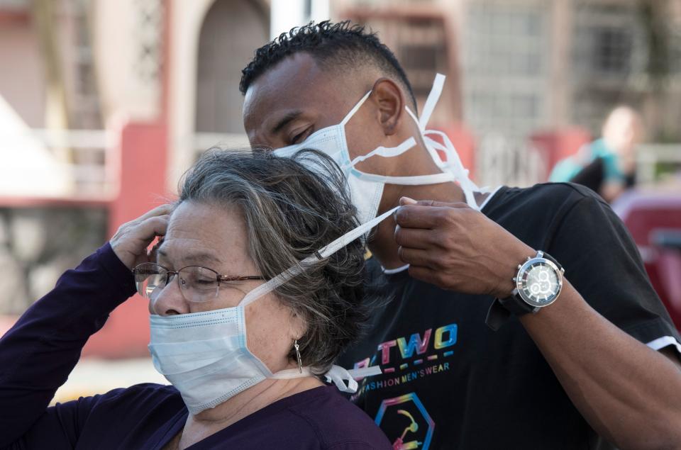 A man puts a face mask on a woman as a preventive measure against the spread of the new coronavirus, COVID-19, in San Jose, on March 16, 2020. - Latin America has registered more than 800 cases and seven deaths, according to an AFP count, after the Dominican Republic became the latest nation to report a fatality. (Photo by Ezequiel BECERRA / AFP) (Photo by EZEQUIEL BECERRA/AFP via Getty Images)