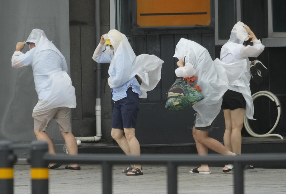 People struggle in the rain and wind as the tropical storm named Khanun approaches to the Korean Peninsular, in Busan, Thursday, Aug. 10, 2023. (AP Photo/Ahn Young-joon)